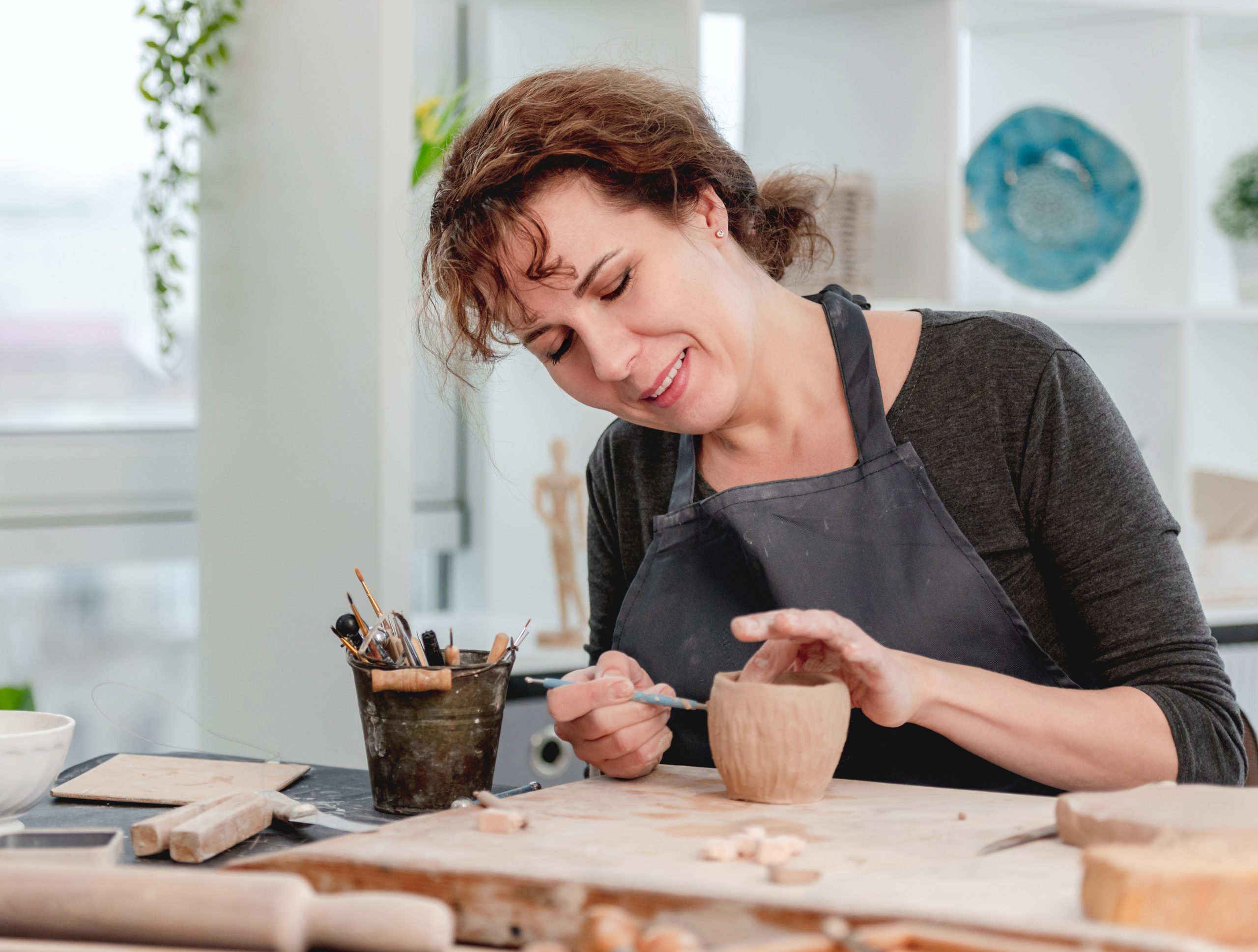 Smiling woman potter working at workshop